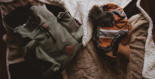 橙色针织帽旁边的灰色背包 · 免费素材图片