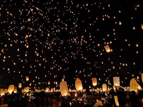 一群人在夜间将纸灯笼扔在天空上 · 免费素材图片