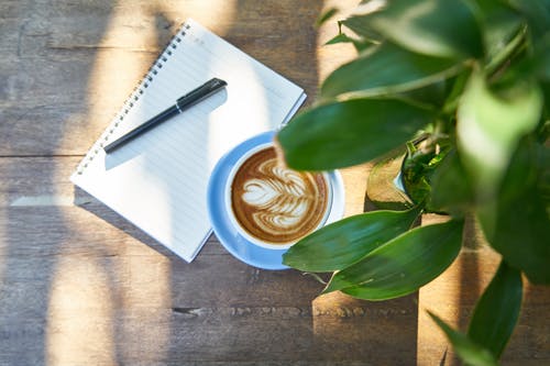 白色笔记本旁边的咖啡拿铁咖啡 · 免费素材图片