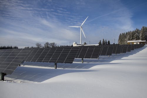 晴朗的天空下的风车在雪地上的太阳能电池板 · 免费素材图片