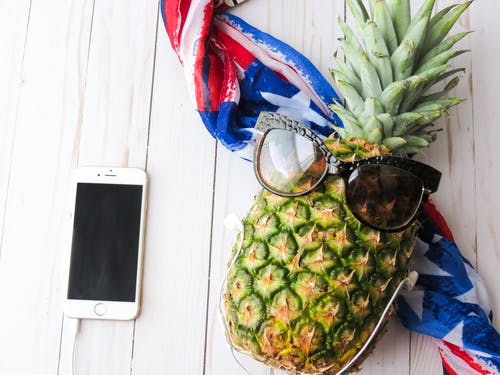 成熟的菠萝与棕色太阳镜近黄金iphone 6白色表面上 · 免费素材图片