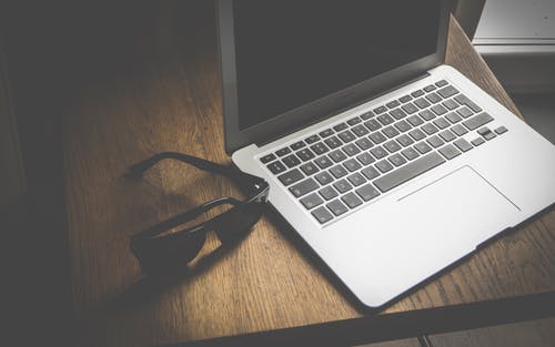 Macbook Air附近的黑色飞行员太阳镜 · 免费素材图片