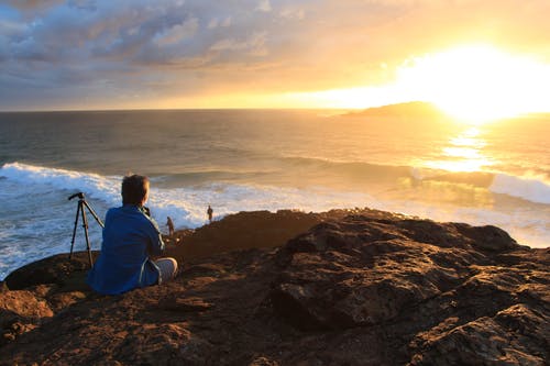 坐在悬崖上看日落的人 · 免费素材图片