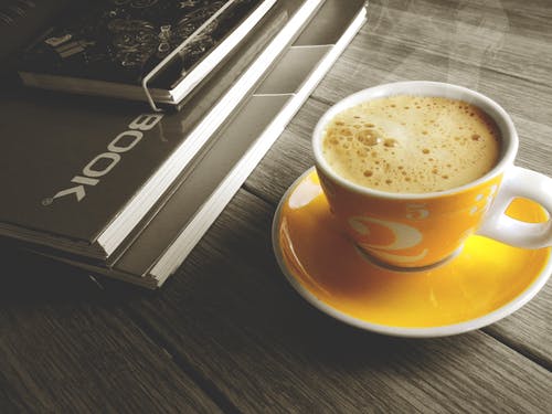 在茶碟顶部的橙色和白色杯子装满咖啡 · 免费素材图片
