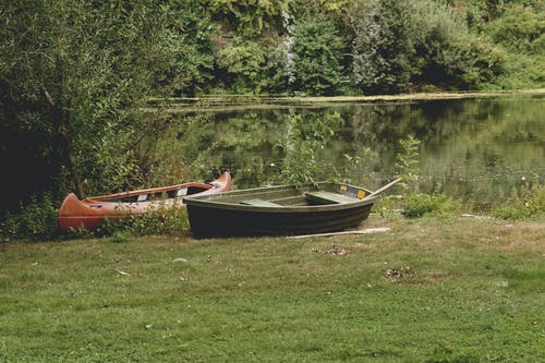 两个黑色和红色的什锦的小船在草地上 · 免费素材图片