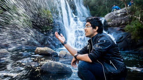 男子坐在瀑布 · 免费素材图片