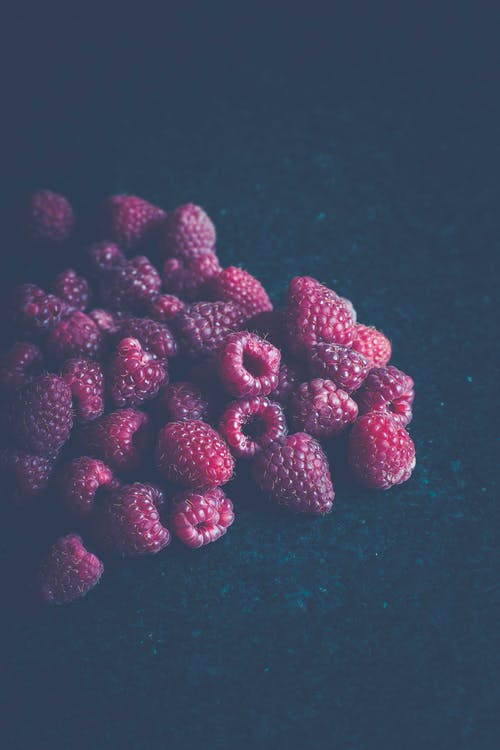 蓝色表面上的红树莓果实 · 免费素材图片