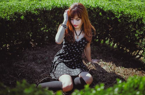 女人坐在灌木丛旁的地上 · 免费素材图片