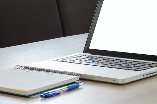 银色便携式计算机旁边的蓝色单击笔 · 免费素材图片