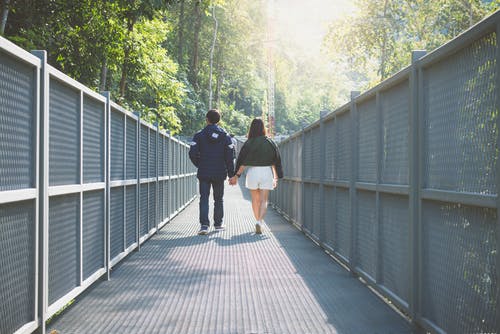 男人和女人牵着的手走在灰色的桥上 · 免费素材图片