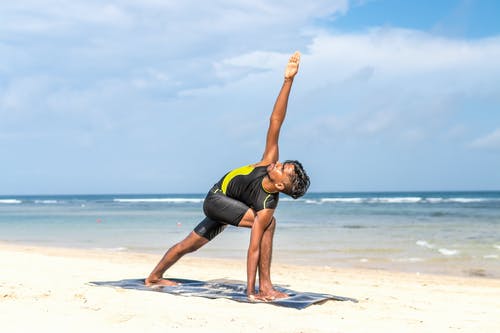男人做瑜伽姿势在海边旁边的蓝色垫子上 · 免费素材图片