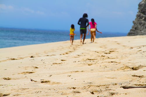 男人，女人和女孩在水体附近的海边散步 · 免费素材图片