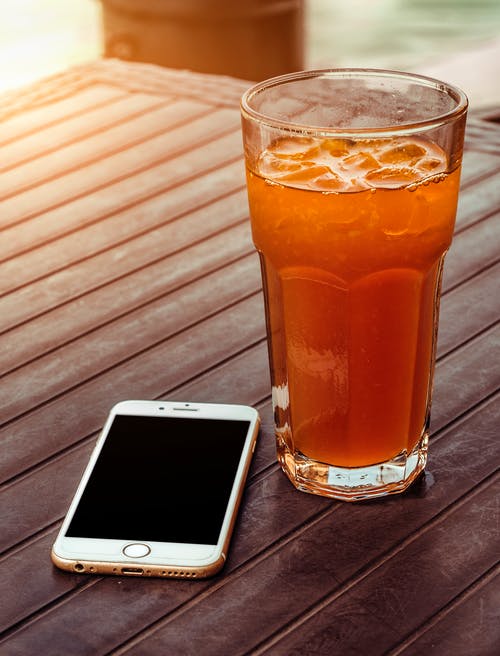除金iphone 6棕色木制的桌子上的透明水杯橙汁 · 免费素材图片