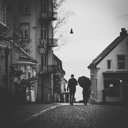 男人旁边的女人在伞下在人行道上行走的灰度照片 · 免费素材图片
