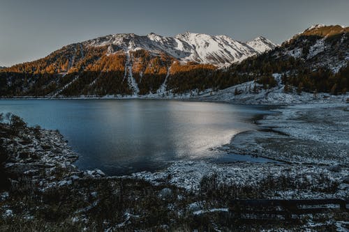 水体旁边的棕色和白色高层山 · 免费素材图片