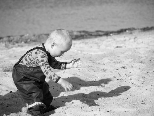 小孩在沙滩上的灰度摄影 · 免费素材图片