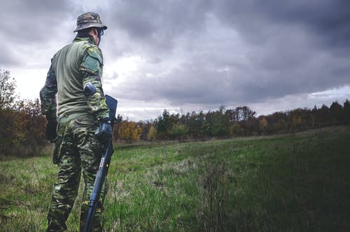 手持黑色狩猎步枪的伪装士兵服的男人 · 免费素材图片