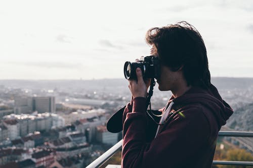 褐红色外套的人使用照相机 · 免费素材图片