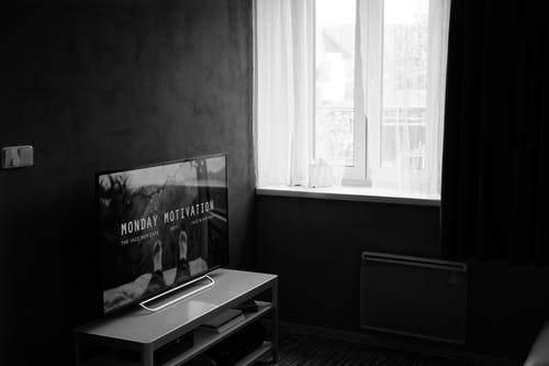 平板电视在木制电视架上的灰度照片 · 免费素材图片