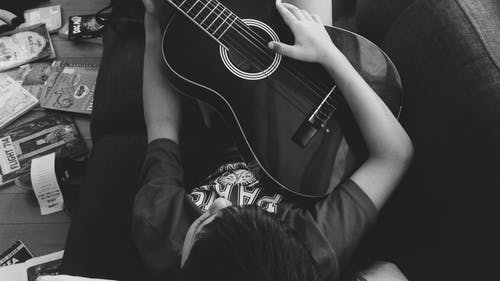 弹吉他躺在灰度摄影在沙发上的人 · 免费素材图片
