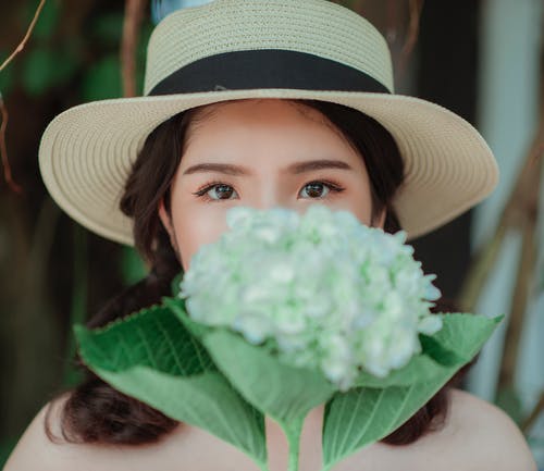 女人戴着白帽子手捧花 · 免费素材图片