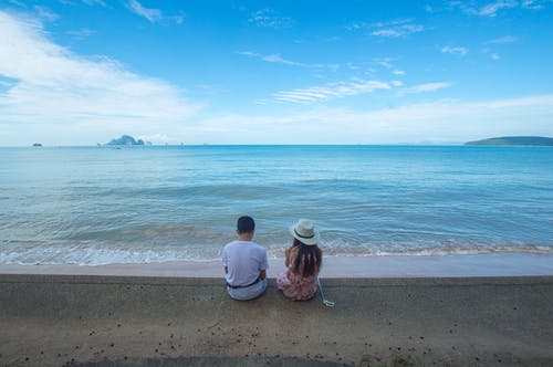 男人和女人坐在海边 · 免费素材图片