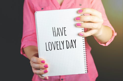 女人穿着粉红色的连衣裙，拿着绘图笔记本与有一个可爱的日子标志 · 免费素材图片