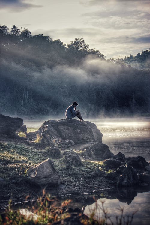 灰色的男人坐在岩石巨石上 · 免费素材图片