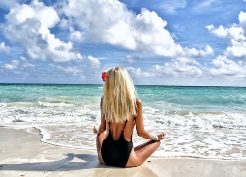 穿着黑色monokini冥想在大海在蓝色和白色的天空下的女人 · 免费素材图片