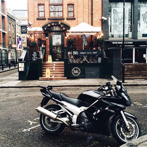 黑色和白色的yamah运动自行车停在外面的皮带商店门面 · 免费素材图片