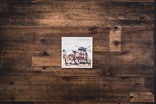 棕色木质表面上的两个什锦的自行车图 · 免费素材图片