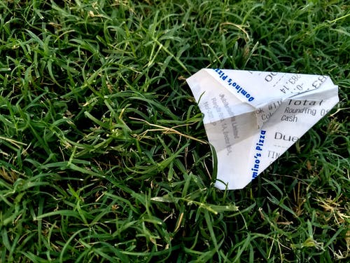 收据折叠成纸飞机在草地上 · 免费素材图片