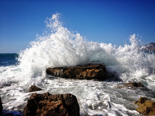 岩石的海滨与海浪在蓝蓝的天空下 · 免费素材图片