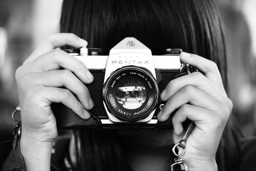 女人在灰度摄影中拿着单反相机 · 免费素材图片