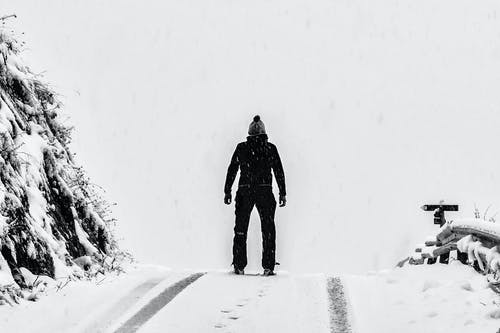 站在山旁边的白雪覆盖的地面上的人 · 免费素材图片