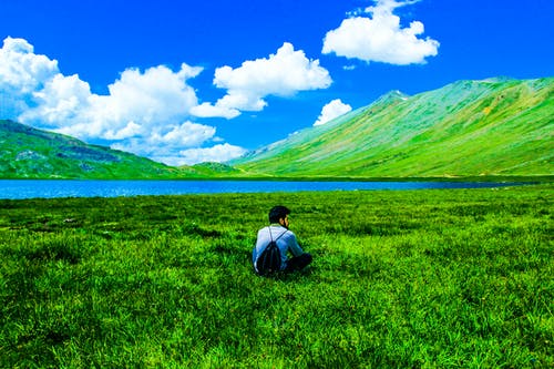 男孩坐在绿草地上 · 免费素材图片