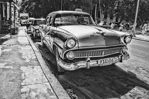 老式汽车在人行道旁的灰度摄影 · 免费素材图片