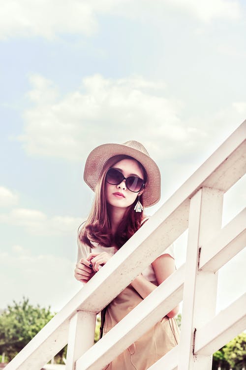 戴着灰色的太阳帽在白色的栅栏前的女人 · 免费素材图片