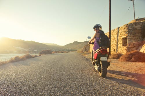 在日出期间在沥青路面上行驶的女人骑小型摩托车 · 免费素材图片