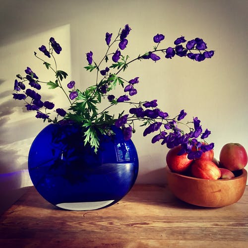 桌上苹果果实附近的紫色花瓣花的布置 · 免费素材图片