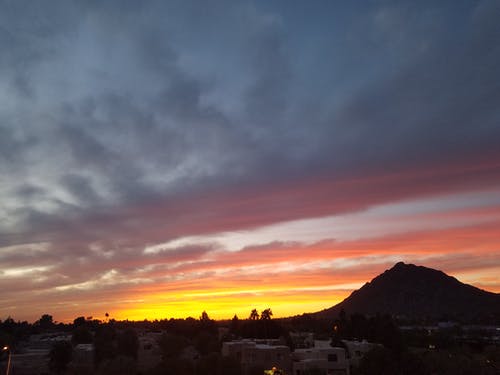 黄昏期间的灰色和白色建筑物和布朗山 · 免费素材图片