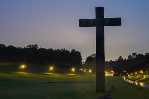 棕色十字雕像在绿色草地上与夜间开启的光 · 免费素材图片
