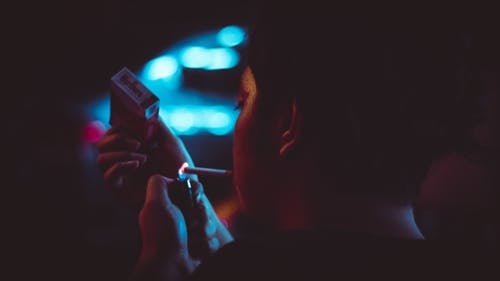 男子在夜间在倾斜移位镜头照相中点燃一支香烟 · 免费素材图片
