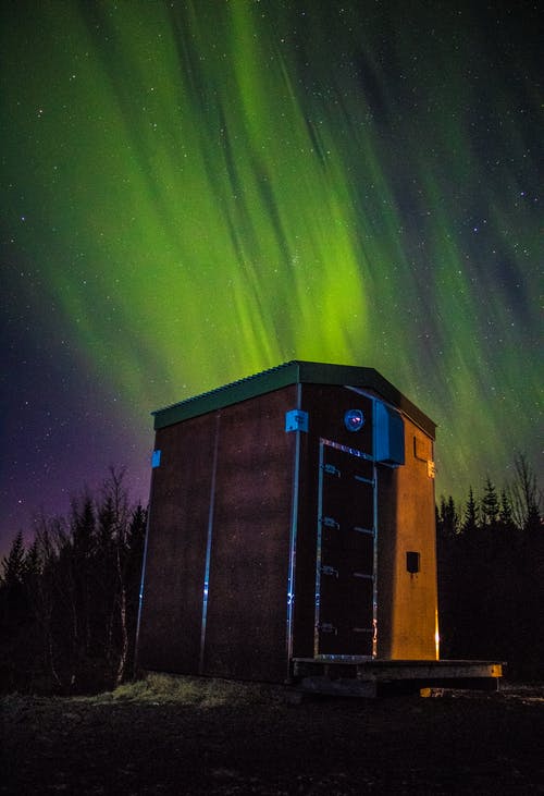 木制棚屋在北极光下的照片 · 免费素材图片