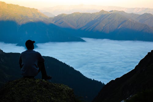 多云的天空之上的悬崖边缘上的人 · 免费素材图片