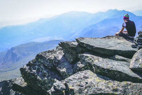 一个男人坐在岩石上的摄影 · 免费素材图片