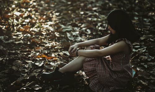 一个女人坐在地上的照片覆盖着干树叶 · 免费素材图片