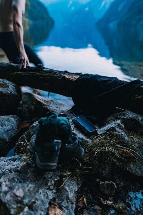 一双黑色的鞋子和黑色的智能手机，在棕色的石头上 · 免费素材图片