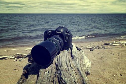 黑色佳能单反相机附近海岸 · 免费素材图片