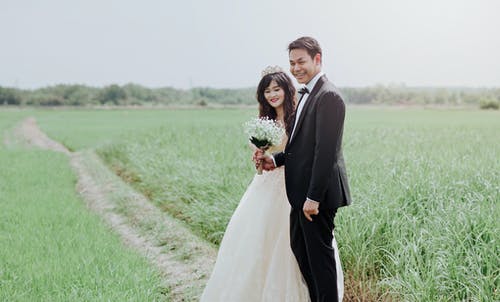 男人和女人在稻田之间穿婚纱和西装 · 免费素材图片